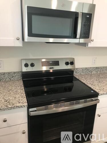 A kitchen with a black stove top oven and a silver microwave above it.