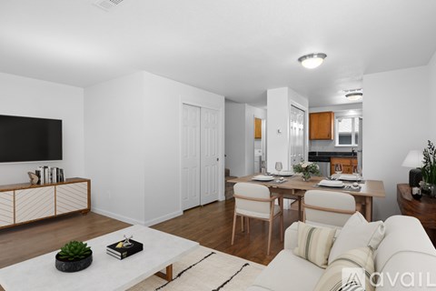 A living room with a white couch, a coffee table, and a television on the wall.