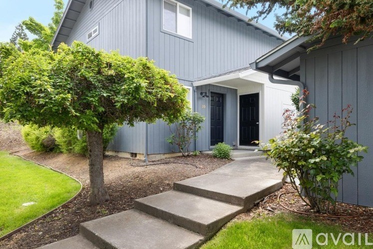 A house with a grey exterior and a tree in front of it.
