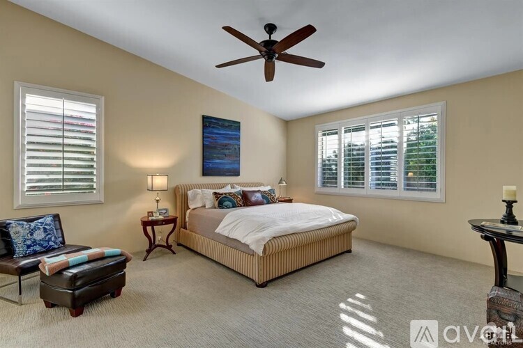 A bedroom with a bed, a chair, and a painting on the wall.