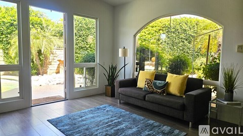 A living room with a couch and a rug in front of a large window.