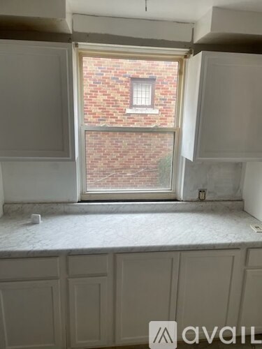 A kitchen with white cabinets and a window overlooking a brick building.