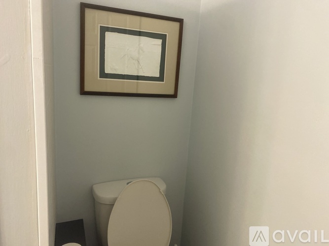 A toilet is in a small bathroom with a picture frame on the wall.