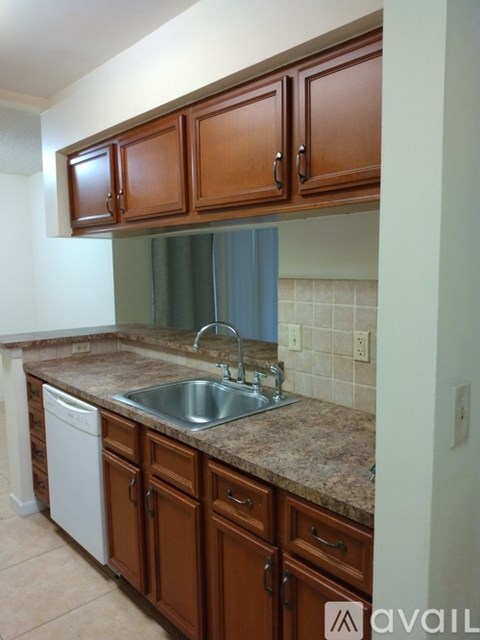 A kitchen with brown cabinets and a granite counter top.