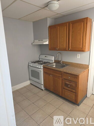 A kitchen with wooden cabinets and a white stove top oven.
