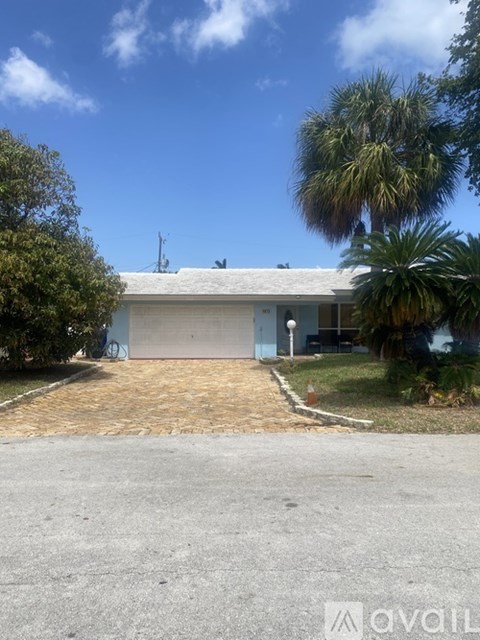 A house with a driveway and a palm tree in front.