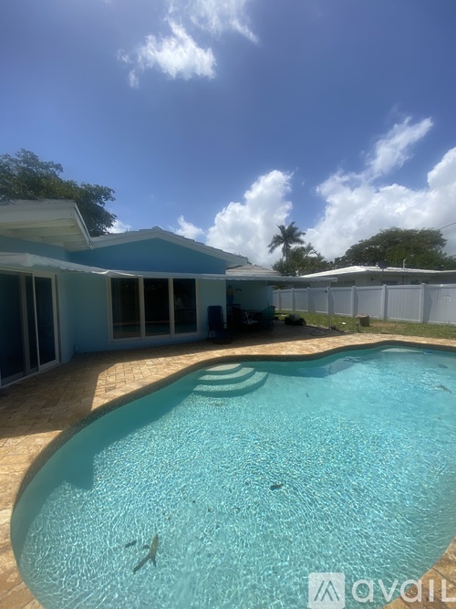 A pool in front of a house with a fence around it.