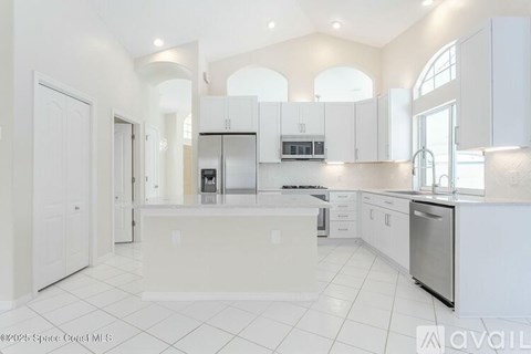 A spacious kitchen with white cabinets and appliances.