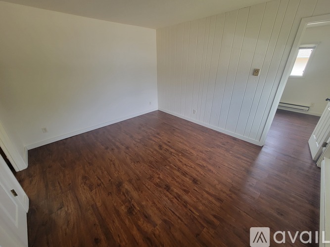 A room with wooden flooring and white walls.