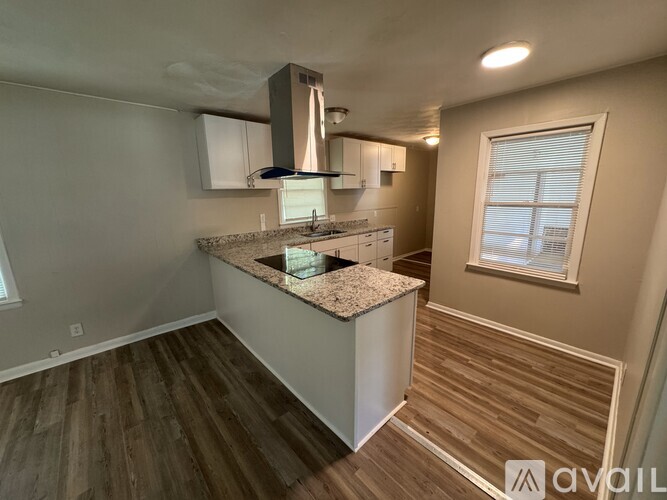A kitchen with a granite countertop and wooden flooring.