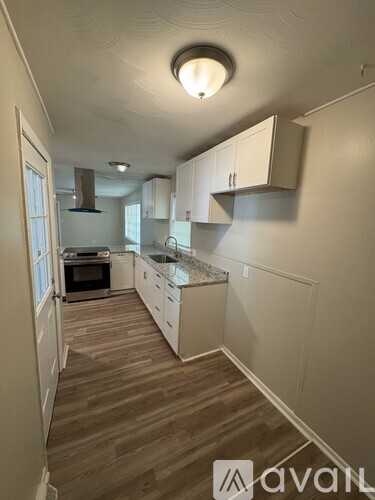 A kitchen with white cabinets and a wooden floor.