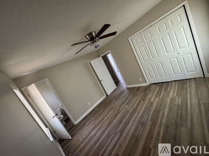 A room with a ceiling fan and a door leading to another room.