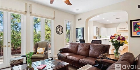 A living room with a brown leather couch and a glass coffee table.