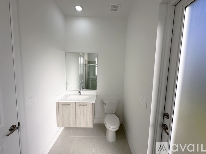 A white bathroom with a sink, toilet, and mirror.
