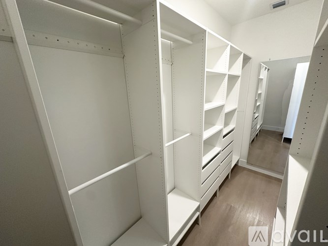 A walk-in closet with white shelving and drawers.