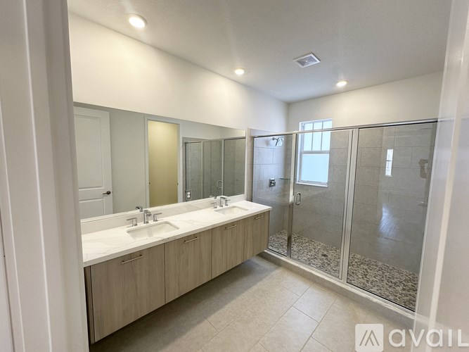 A bathroom with a double sink vanity and a walk-in shower.