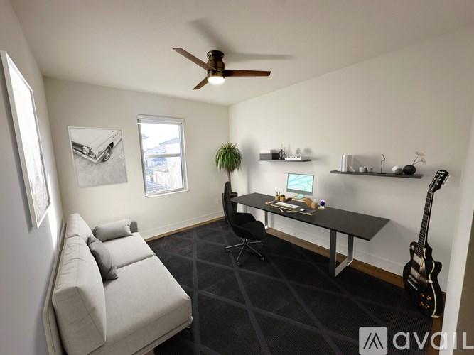 A room with a couch, a table, a guitar, and a ceiling fan.