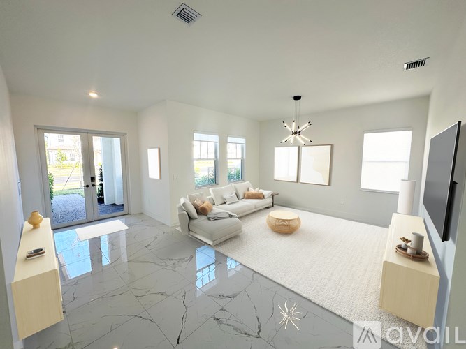 A spacious living room with a white sofa and a television on the wall.