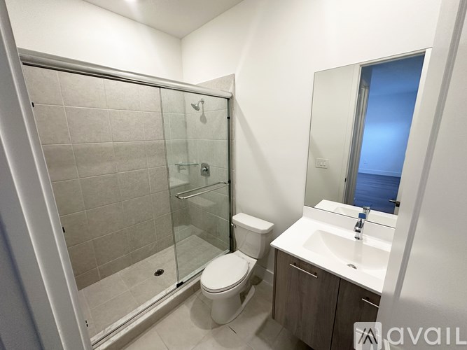 A bathroom with a toilet, sink, and glass shower door.