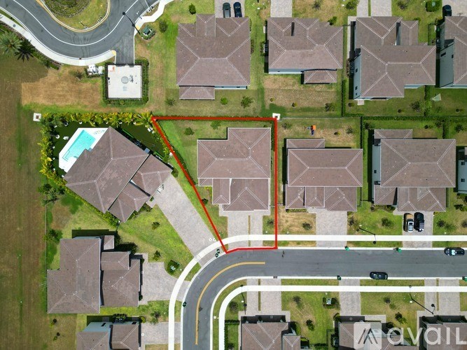 A bird's eye view of a neighborhood with a red outlined property in the foreground.