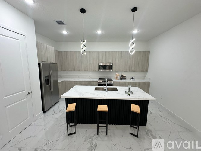 A modern kitchen with a marble countertop and bar stools.