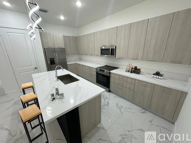 A modern kitchen with a marble countertop and wooden cabinets.