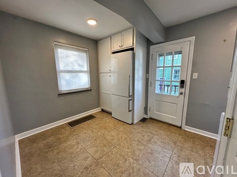 A kitchen area with a white refrigerator and a door leading to another room.
