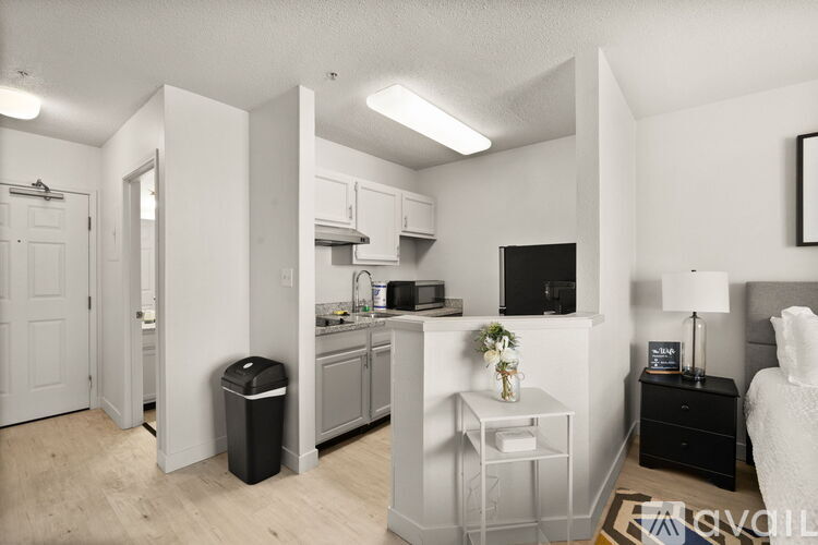 A modern kitchen with a white interior and a dining area with a black table and chairs.