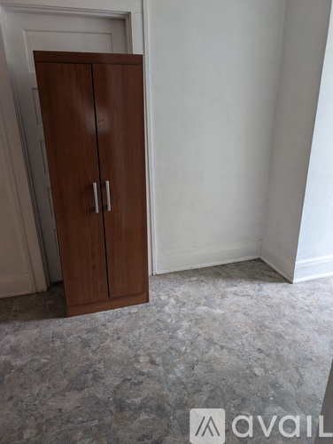 A brown wardrobe with two doors stands in a room with a grey carpet.