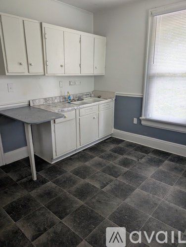 A kitchen with white cabinets and a checkered floor.