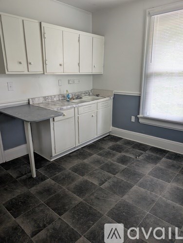 A kitchen with white cabinets and a checkered floor.
