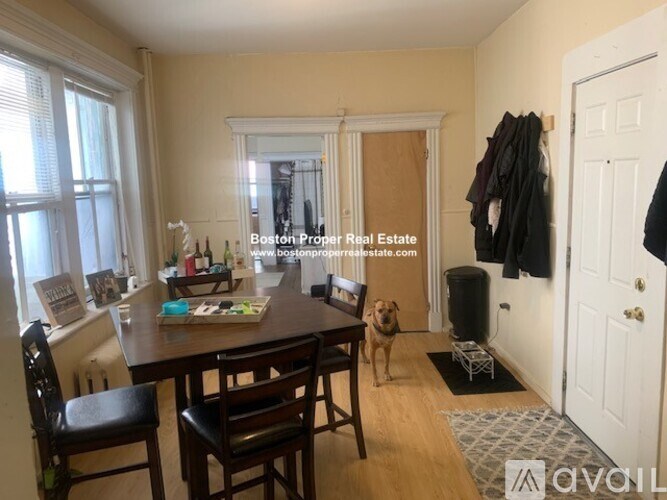 A dining room with a table and chairs and a dog standing in the middle.