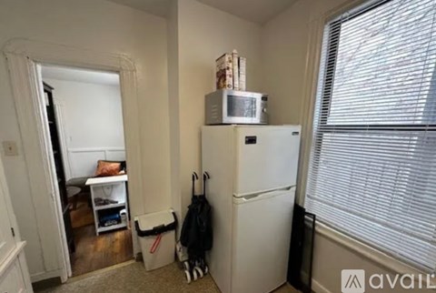 A small kitchen with a white fridge and a microwave on top of it.