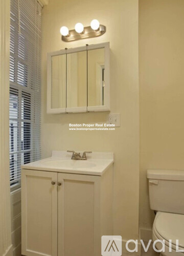 A white bathroom with a toilet, sink, and mirror.