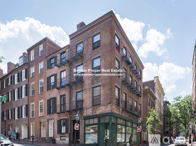 A street view of a red brick building with a green awning and a white door.