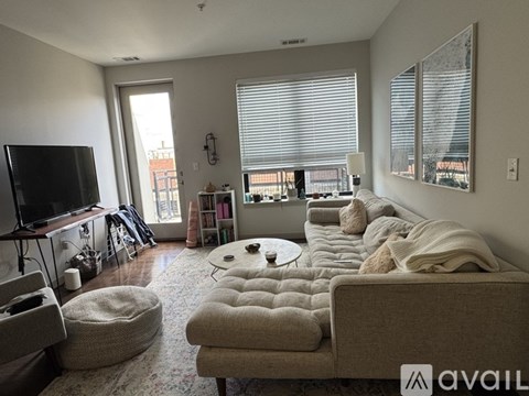 A living room with a couch, ottoman, and television.
