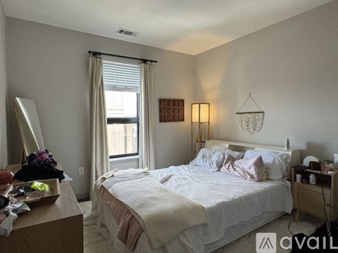 A bedroom with a bed, nightstand, and window.