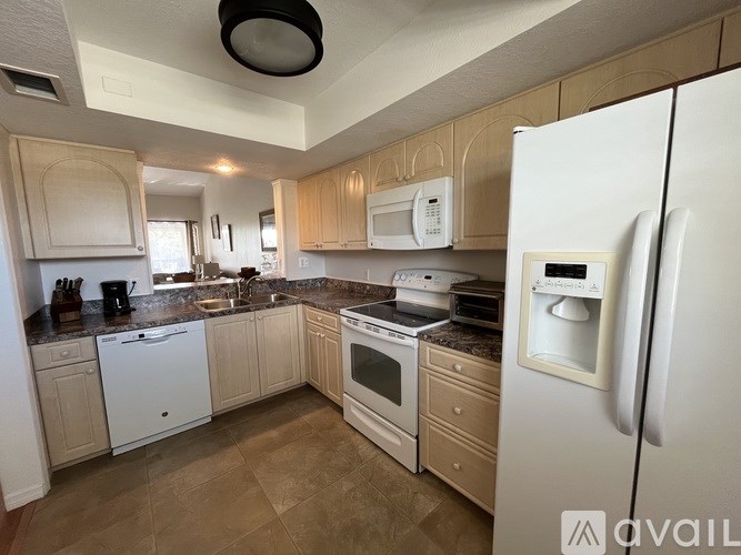 A kitchen with a white refrigerator and wooden cabinets.
