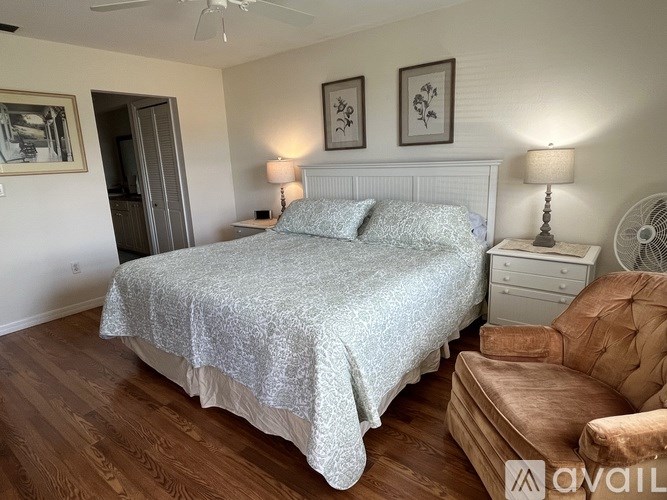 A bedroom with a bed, a chair, and two lamps.