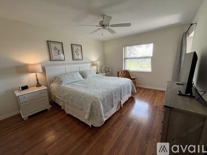 A bedroom with a bed, nightstand, and a ceiling fan.