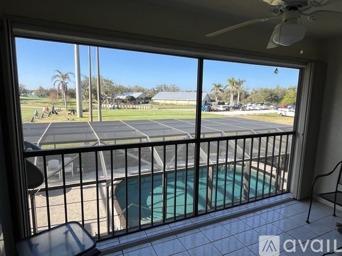 A balcony with a pool table and a view of a parking lot and palm trees.
