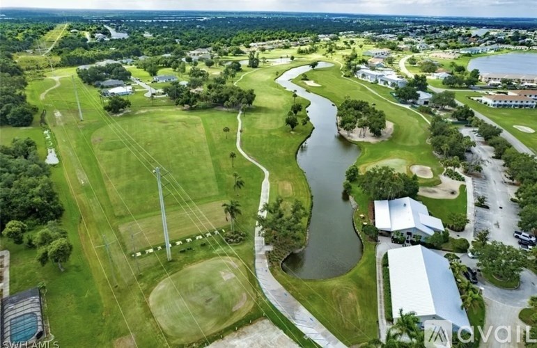 A river flows through a green landscape with buildings on the side.