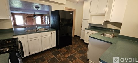 A kitchen with a black refrigerator and white cabinets.