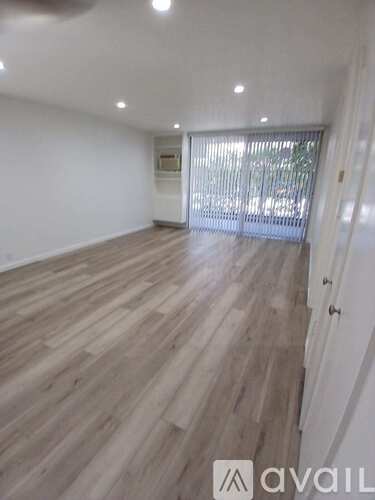 A room with wooden flooring and a window with blinds.
