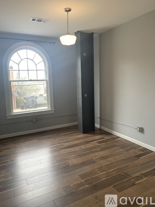 A room with a wooden floor and a large arched window.