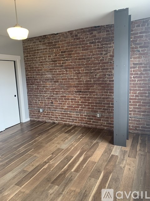 A room with wooden floors and a brick wall.