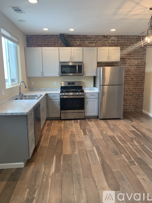 A kitchen with wooden floors and a brick wall.