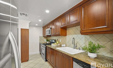 A kitchen with wooden cabinets and a stainless steel refrigerator.