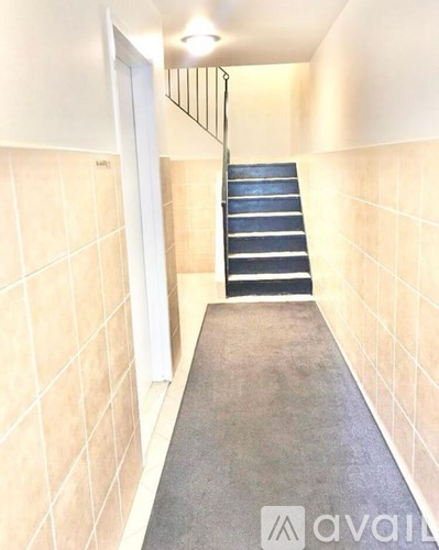 A hallway with a staircase and tiled walls.