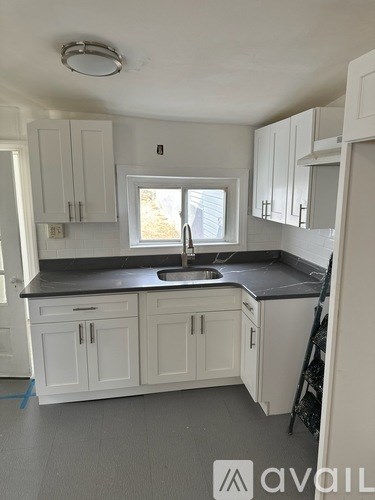 A kitchen with white cabinets and a black countertop.